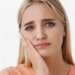 girl holding face with toothache